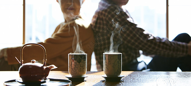 背靠背坐在起居室茶桌旁的老夫妻图片