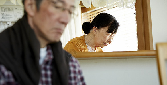 老男人坐着老妇人在厨房忙碌图片