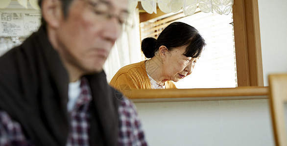 老男人坐着老妇人在厨房忙碌背景图片