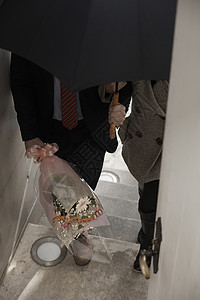 女孩牵着打着伞拿着花的男友上楼图片