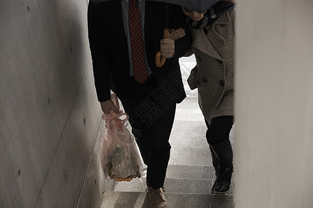 女孩牵着打着伞拿着花的男友上楼图片