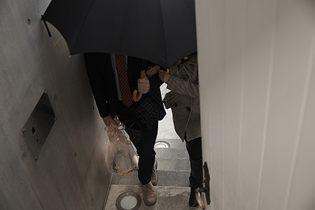 女孩牵着打着伞拿着花的男友上楼图片素材