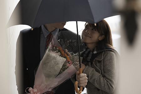女人和拿着伞和花束的男人对视图片