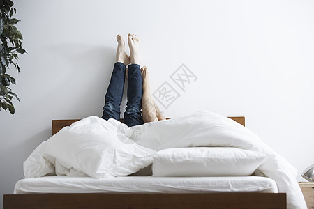 躺在床上的情侣把脚抬到墙上图片