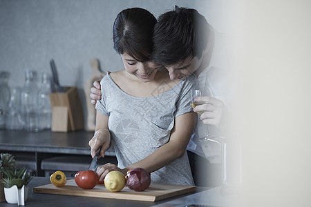 端着酒杯的男人搂着切菜的女人图片素材