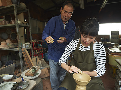 陶瓷师傅指导体验陶瓷制作的女人图片
