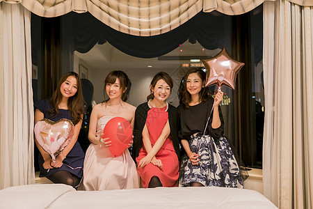 朋友聚会女人们在卧室拿着气球看着镜头微笑图片