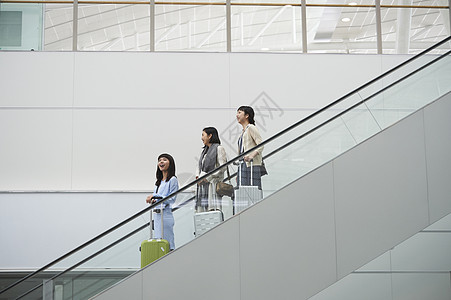 三名女性在机场航站楼拖着行李图片