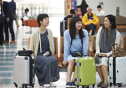 带着行李坐在航空站候车室的女人们图片