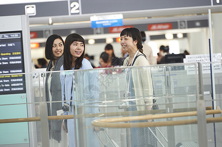 拿着行李走在航空站的女人们图片