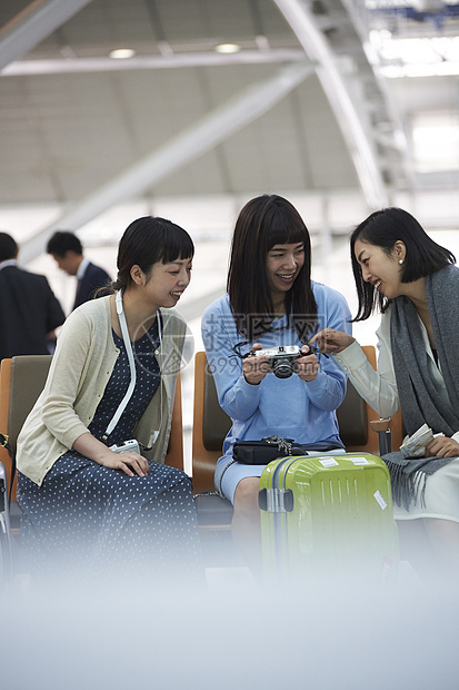 拿着行李坐在航空站候车室椅子上的女人们图片