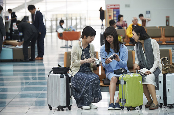 拿着行李坐在航空站候车室椅子上的女人们图片