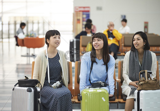 拿着行李坐在航空站候车室椅子上的女人们图片