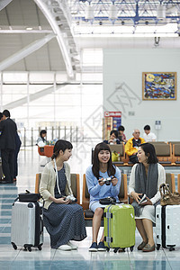 拿着行李坐在航空站候车室椅子上的女人们图片