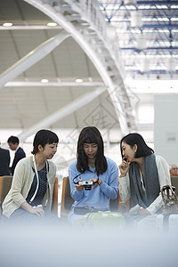 拿着行李坐在航空站候车室椅子上的女人们图片