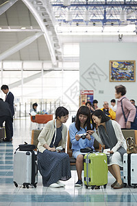 拿着行李坐在航空站候车室椅子上的女人们图片