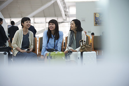 拿着行李坐在航空站候车室椅子上的女人们图片