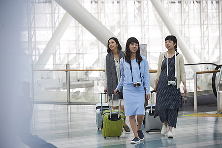 拿着行李走在航空站的女人们图片