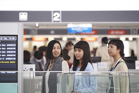 拿着行李走在航空站的女人们图片