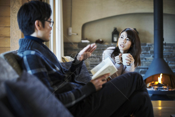 在小屋壁炉边女人和拿着书的男人说笑轻井泽图片