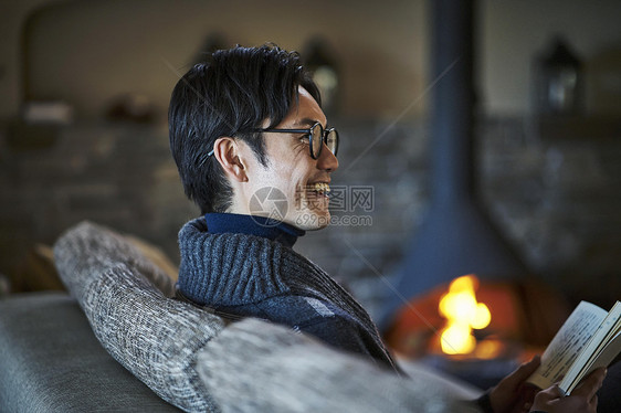 在小屋壁炉边拿着书的男人在笑轻井泽图片