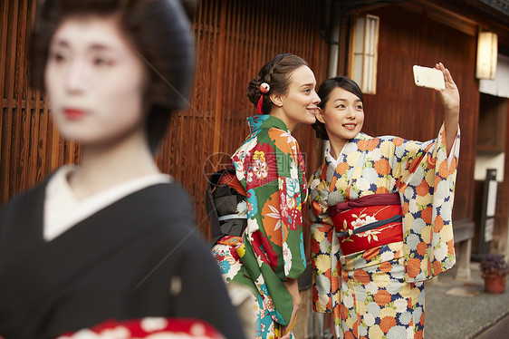 合影的游客路过日本传统歌舞艺妓图片