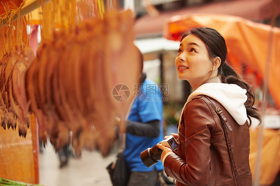 在早晨集市上拿相机拍照的女子图片