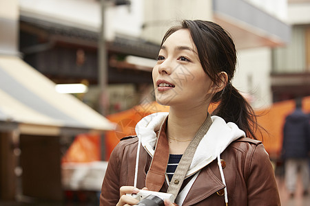 女性拿着照相机在室外散步图片