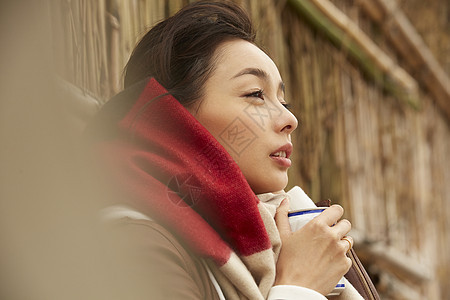 戴着围巾双手捧着杯子的女性图片