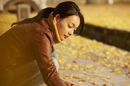 女人蹲在地上捧着银杏叶图片