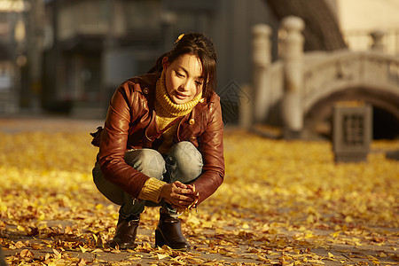 女人蹲在地上捧着银杏叶图片