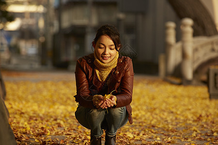 女人蹲在地上捧着银杏叶图片