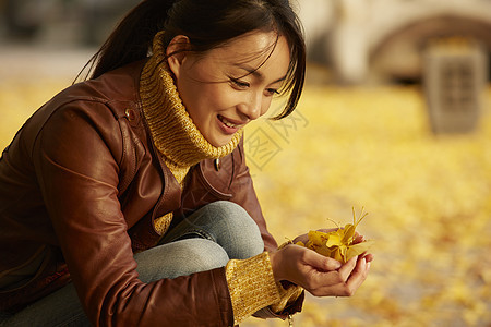 女人蹲在地上捧着银杏叶图片