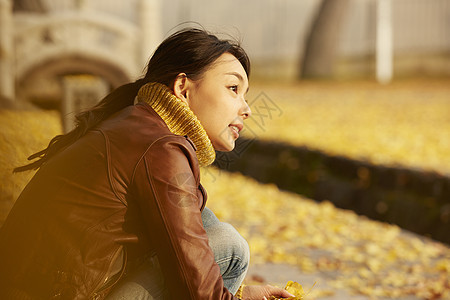 女人蹲在地上捧着银杏叶图片