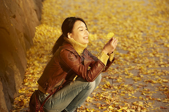 女人蹲在地上拿着银杏叶图片