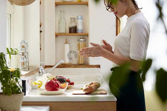 在窗边料理台制作午饭的女人图片