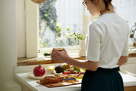 在窗边料理台制作午饭的女人图片