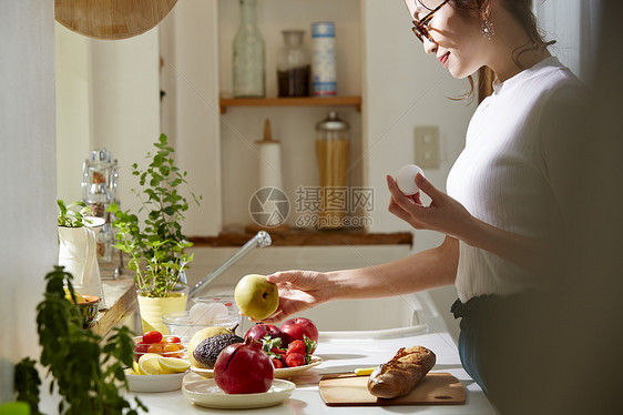 在窗边料理台制作午饭的女人图片