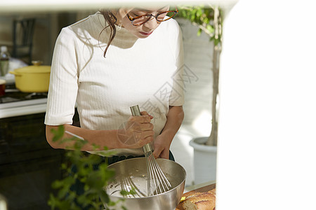 在窗边料理台制作午饭的女人图片