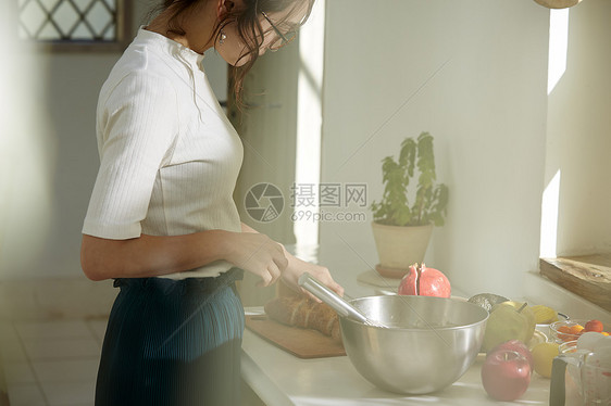 在窗边料理台制作午饭的女人图片