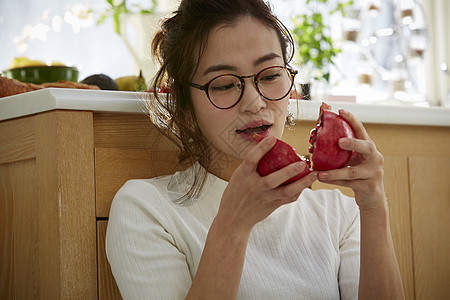 在窗边料理台蹲下看切开的石榴的女人图片