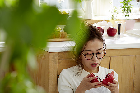 在窗边料理台蹲下看切开的石榴的女人图片