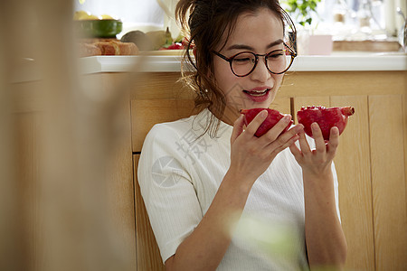 在窗边料理台蹲下看切开的石榴的女人图片