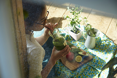 坐在院子里晒太阳喝饮料的时髦美女 图片