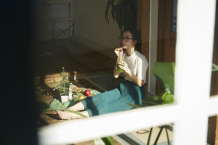 坐在院子里晒太阳喝饮料的时髦美女 图片