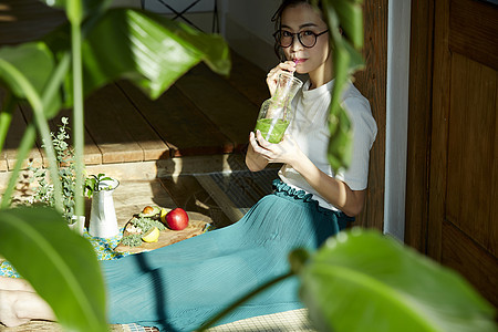 坐在木地板上晒着太阳喝奶昔的女人的妇女图片