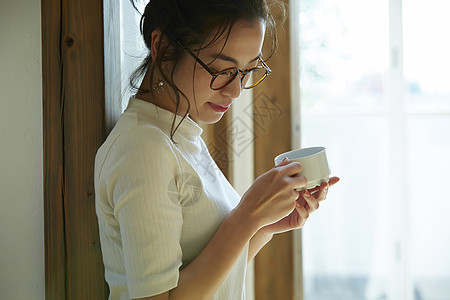 女人站在门边晒着太阳喝咖啡图片