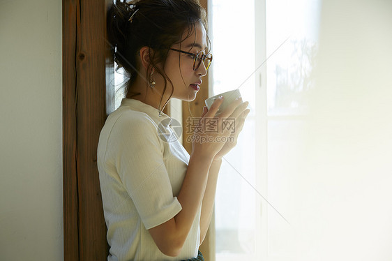 女人站在门边晒着太阳喝咖啡图片