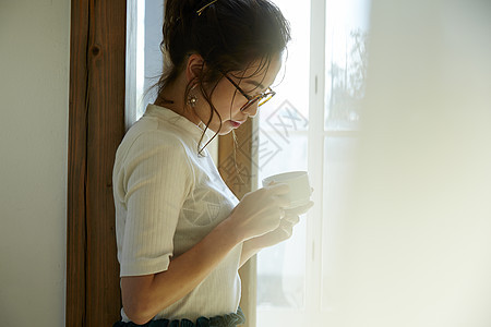 女人站在门边晒着太阳喝咖啡图片