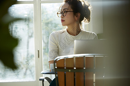 女人坐在窗边的桌上喝咖啡工作图片